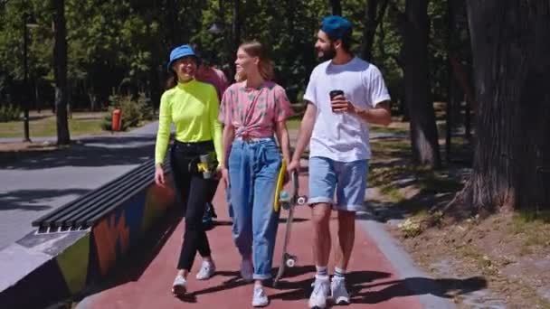 Charismatische und gut aussehende Teenie-Freunde, die beim Spaziergang durch den städtischen Skatepark gesellig miteinander ins Gespräch kommen, lächeln breit. 4k — Stockvideo