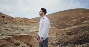 Harika görünümlü bir adam kameranın önünde büyük bir gülümseme ile doğanın muhteşem manzarasının ortasında heyecanlanıyor.