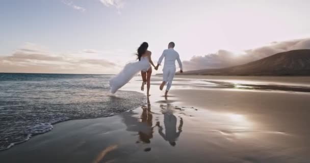 Дивовижний краєвид з гірським і морським чоловіком і жінкою, що йде по морю вони обіймають один одного руки — стокове відео