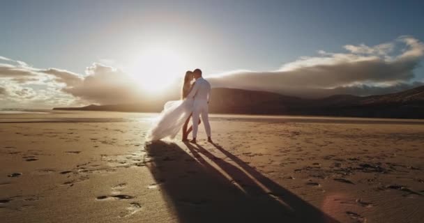 Charismatische man en vrouw romantisch knuffelen elkaar en genieten van het moment samen aan het strand — Stockvideo