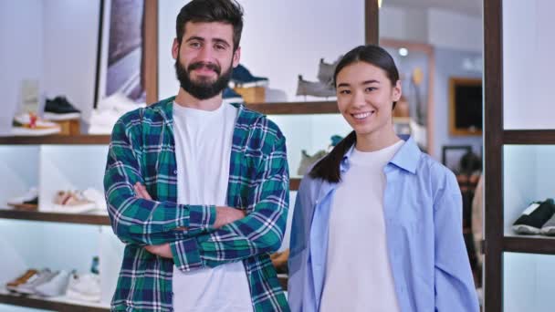 Mosolygó nagy eladók egy cipőboltban áll a kamera előtt, és mosolyogva nagy fehér fogak — Stock videók