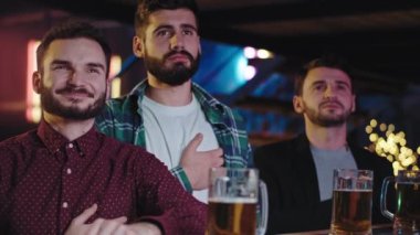 Bir spor barı grubunda, en sevdikleri takımın maçını bitirirken televizyona odaklanan taraftarlar birbirlerini kucakladıkları için çok mutlular.