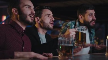 Kameraya yakın, karizmatik yakışıklı erkekler bir barda TV 'de maç izleyip bira içerken çok yoğun ve heyecanlılar.