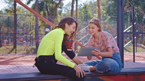 Lächelnd große glückliche Freunde Damen im Park, während sie Kaffee trinken mit elektronischen Tabletten, um einige zu beobachten — Stockvideo