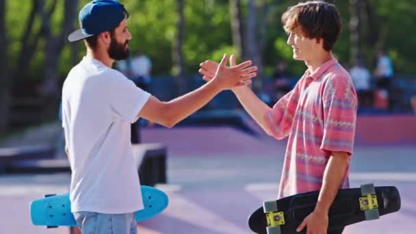 Encontro no meio do parque de skate urbano dois caras amigos que conversam juntos depois que eles vão ter passeio com skate — Vídeo de Stock