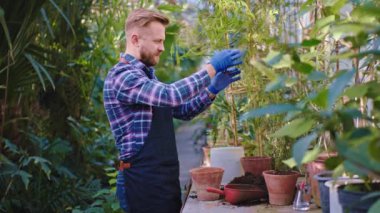 Kendi serasındaki çekici bahçıvan küçük dekoratif bir bitki alıp dikkatlice ve tutkuyla bir saksı dikmiş. ARRI Sinema Kamerasında Çekim