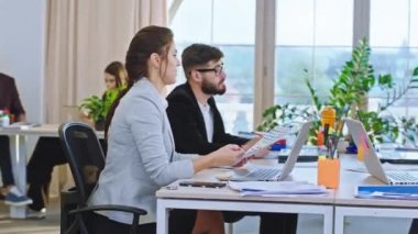 Modern bir ofiste, panoramik manzaralı bir grup yönetici ve ofis çalışanı stratejik bir iş planı yapar ve bazı liderlik fikirlerini tartışırlar. 4k