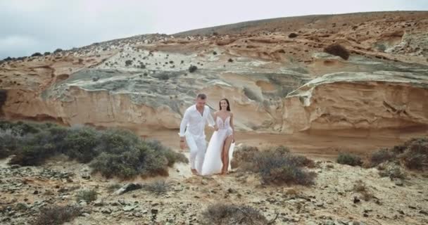 Guy a dáma procházející se skalami v úžasné krajiny pohled mají na sobě krásné šaty kód těší okamžik spolu. 4k — Stock video