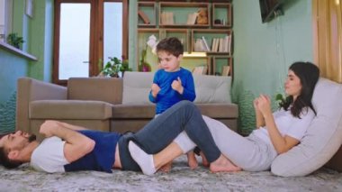 Mutlu bir aile günü çocuklarla birlikte geçirir. Anne ve baba yere uzanır, spor yapar, eğlenir.