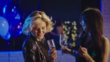 Doğum günü partisinde ışıl ışıl kıyafetli iki kadın parti atmosferinin tadını çıkarıyor. Rahatlamış ve mutlu.