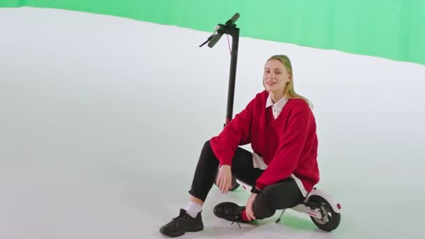 Fantastisk dam med ett perfekt leende ta en sitta på sin elektriska skoter i en grön bakgrund studio koncept kroma nyckel — Stockvideo