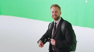 İyi görünümlü genç bir ofis çalışanı kameranın önünde poz veriyor. Modern elektrikli scooterının yanında büyük yeşil bir arka plan stüdyosunda.