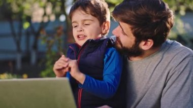 Bahçede babasıyla birlikte gülümseyen küçük bir çocukla iyi vakit geçir. Küçük çocuk babasına bazı fikirler söylüyor. Tüm notları çimlerin üzerine otururken dizüstü bilgisayara yazıyorlar.