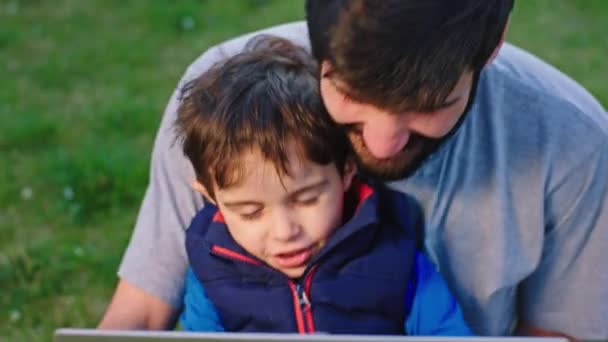 Портрет крупным планом весело время молодой папа играет со своим маленьким сыном в саду они наслаждаются время вместе чувствовать себя счастливым и расслабленным — стоковое видео