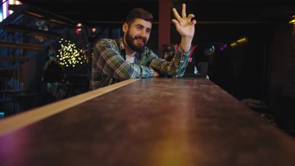 På en bar bord snygg kille ler och glad beställa ett glas dryck upphetsad han börjar dricka — Stockvideo