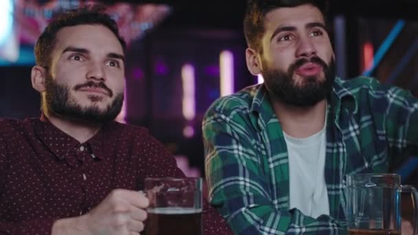 Skoncentrowani charyzmatyczni faceci w barze sportowym oglądają mecz piłki nożnej, emocjonalnie patrzą na telewizję, pijąc kieliszek wina. Zdjęcia z kamery filmowej ARRI — Wideo stockowe