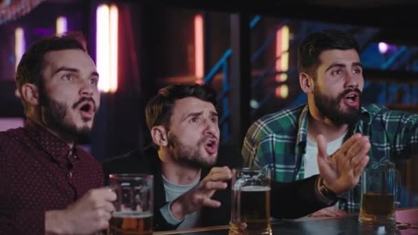 Три хлопці харизматично близькі до фанатів камерного футболу в пабі під час пиття пива, спостерігаючи за матчем, вони такі емоційні в спортивному барі — стокове відео
