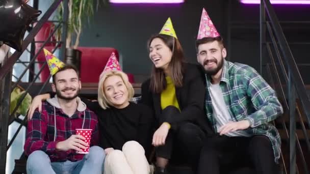 Davanti al gruppo di telecamere di amici multietnici in una moderna biblioteca che celebra un compleanno hanno in mano tazze di compleanno e godersi la serata — Video Stock