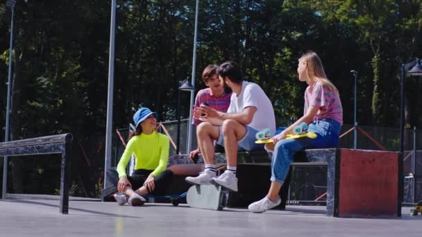 Grupo de amigos senhoras e rapazes se divertir em um parque de skate moderno eles discutem algo sorrindo grande eles vestindo roupas legais. Tiro em ARRI Alexa Mini — Vídeo de Stock