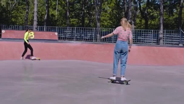 Lindas senhoras roupas elegantes têm um passeio em seu skate em um moderno parque de skate urbano eles gostam de tempo juntos — Vídeo de Stock
