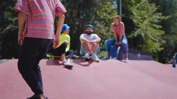 Giornata di sole in un moderno skate park ragazzo è venuto al suo gruppo di amici multietnici si sono seduti tutti insieme sul pavimento prima di iniziare a skateboard tutti insieme — Video Stock