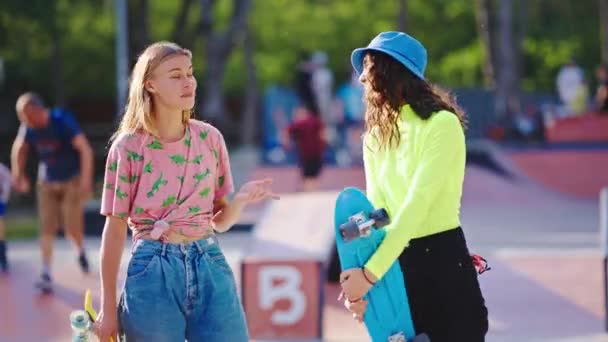 도시 스케이트 공원 한 가운데서 여러 민족으로 이루어진 아름다운 두 여자가 현대 스케이트보드를 들고 카메라 앞에서 토론을 시작 한다 — 비디오