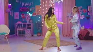 Kameranın önünde pijamalarıyla dans eden mutlu bayanlar yatak odasında yatıya kalırlar. Onlar en iyi arkadaşlardır.