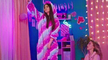 Tek boynuzlu at pijamalı esmer kadın ve güzel pijamalı sarışın bayan yatak odasında biraz selfie çekiyorlar. ARRI Alexa Mini 'de çekilen