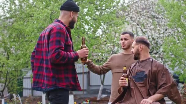 Três amigos carismáticos em casa na quarentena um deles fazer um corte de cabelo também outro cara enquanto bebe cerveja e discutir — Vídeo de Stock
