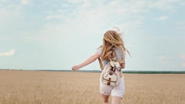 Godere la signora di campagna con i capelli ricci lunghi che corrono attraverso il campo guardando la fotocamera e sentirsi felici — Video Stock