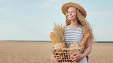 Buğday tarlasında yürüyen güzel bir dişi elinde bir kutu taze ekmekle eğleniyor. ARRI Alexa Mini 'de çekilen