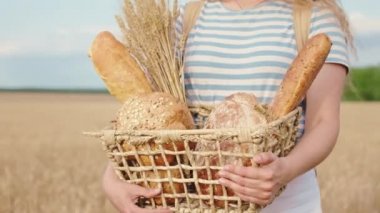 Buğday tarlası sahibinin ortasında elinde taze ekmek kutusuyla büyük bir gülümseme ve uzun saçlı tarım ve çiftçi kavramı ile mutlu hissettiği detaylar. ARRI Alexa Mini 'de çekilen