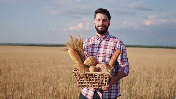 Grande campo di grano giovane sorridente grande agricoltore uomo guardando dritto alla fotocamera e sentendosi eccitato che tiene il pane fresco in una scatola. Girato su ARRI Alexa Mini — Video Stock