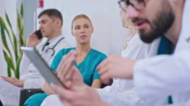 Genç doktorlar ve yetişkinler hastanedeki odalarında dinleniyorlar. Tabletle oynuyorlar, telefonla konuşuyorlar ya da sohbet ediyorlar.