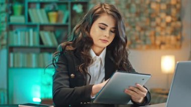 İş yerindeki güzel ofis müdürü kadın konsantre olmuş. Tablete bir şeyler yazıyor. Sonra da dizüstü bilgisayara.