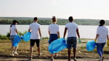 Plaj tarafında, göl kenarındaki gönüllülerin oluşturduğu göl kenarında ellerinde büyük plastik torbalarla yürüyorlar çöpleri topluyorlar ve poşetlerden topluyorlar. 4k