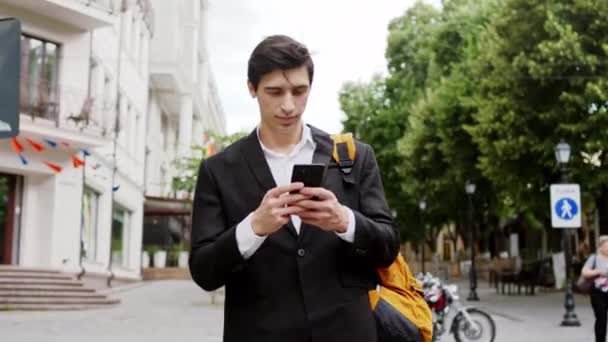 Joven hombre de negocios caminando por la calle tomar su teléfono y y y contestando él comienza a tener una conversación — Vídeo de stock