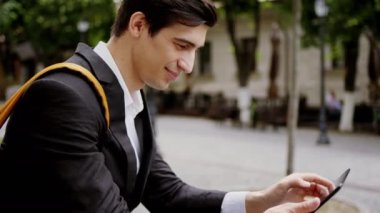 Karizmatik öğrenci cadde merdivenlerine oturur ve elektronik tabletini alır. Bazı notlar alın. 4k