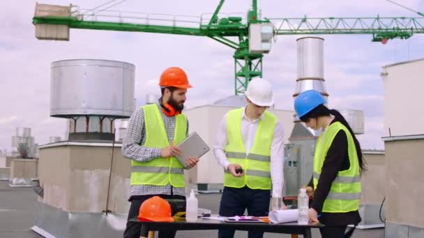 안전 헬멧을 쓰고 잘 생긴 젊은 기술자들과 건축가들은 건설 현장의 꼭대기에서 그들이 가지고 있는 몇 가지 계획을 분석하며 건축 작업을 보러 간다. ARRI 알렉사 주사 — 비디오