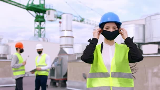 Concetto di Coronavirus 2019 bella signora ingegnere sul tetto del cantiere indossando una maschera protettiva sul viso davanti alla telecamera — Video Stock