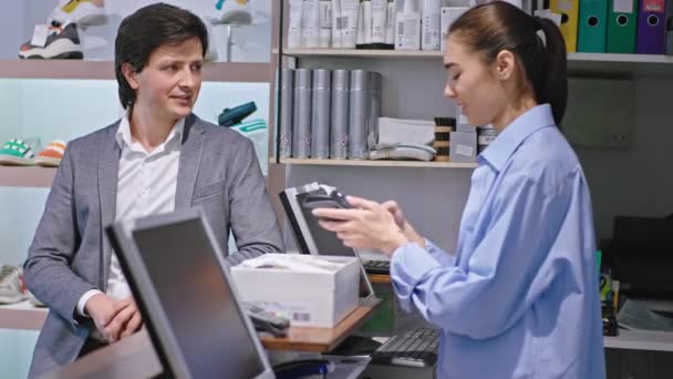 Atrakcyjny lady azjatycki patrząc sprzedawca Dyskusja z klientem w obuwniczym przygotowuje terminal dla klienta do zapłaty kartą kredytową — Wideo stockowe