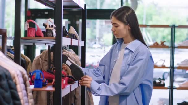 Belle jeune femme client ont une journée shopping dans un magasin de chaussures, elle jeter un oeil à travers les étagères de chaussures — Video