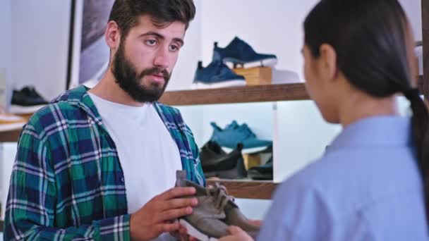 Gros plan en face de la caméra gars avoir une conversation avec sa petite amie ils sont dans un magasin de chaussures acheter des chaussures ensemble ils ont un visage heureux — Video