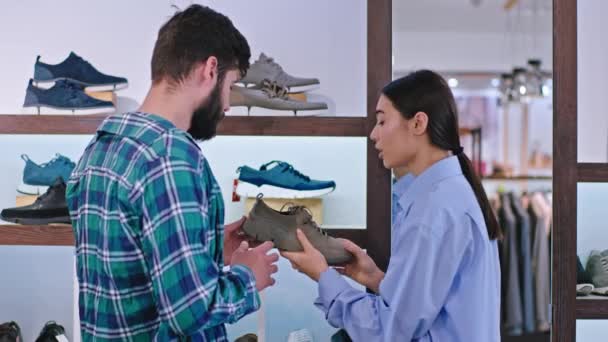 Modern shoe shop handsome guy customer try to find best shoes for him he discussing with the seller from the shop asian lady — Stock Video
