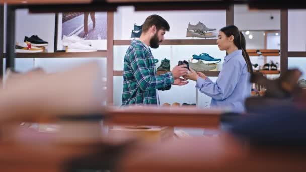 W nowoczesnym sklepie obuwniczym konsultantka młoda kobieta i klient rozmawiają o tym, aby wybrać odpowiednie buty — Wideo stockowe