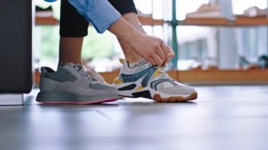 Kanepedeki ayakkabı dükkanındaki bayan. Renkli spor ayakkabıları giyen yeni bir çift deneyin.