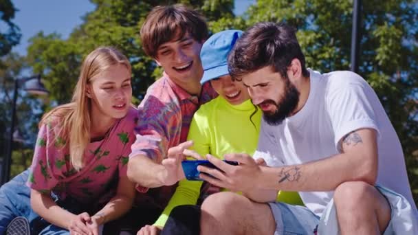 Χαμογελώντας μεγάλους χαρισματικούς φίλους πολυεθνική έξω στο πάρκο έχουν μια συζήτηση, ενώ κοιτάζοντας μέσα από τη σύγχρονη έννοια smartphone του τρόπου ζωής του δρόμου και την εκπαίδευση των μέσων ενημέρωσης — Αρχείο Βίντεο