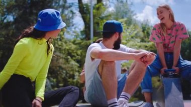 Kentsel bir kaykay parkında, heyecanlı erkekler ve bayanlar birlikte vakit geçirmekten zevk alıyorlar. Kaykay sürmeye başlamadan önce sosyalleşiyorlar.