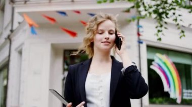 Sokakta yürürken ve iş kadınıyla konuşurken kıvırcık sarı saçları vardı ve elinde dijital tablet vardı.