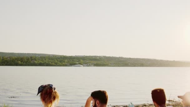 Guten Sommertag am See: Eine Gruppe Jugendlicher lässt es sich nach dem Aufräumen gut gehen — Stockvideo